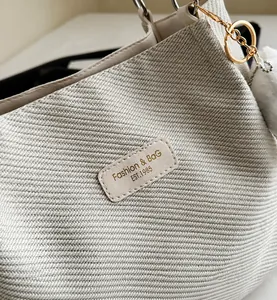 Primer plano de la textura de tela tejida beige con etiqueta de cuero y hebilla dorada