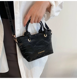 Detail van de zwarte schoudertas met gouden FASHION tekst en een geknoopte hendel