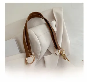 Detail of comfortable brown leather handles and gold metal ring on woven straw tote bag