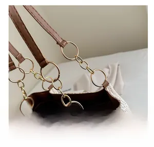 Close-up of golden metal rings connecting the brown leather strap to the woven tote bag