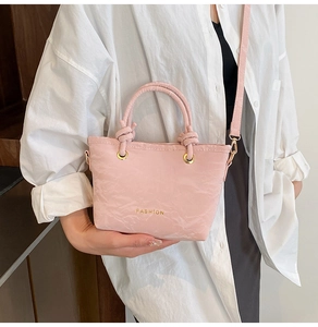 Detail van een lichtroze mini tote met geplooide textuur en gouden knoopgrepen