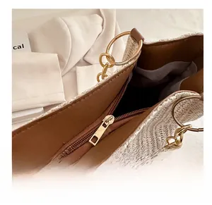 Detail of woven tote bag with smooth gold metal zipper and brown leather trim