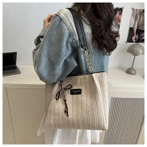 Detail of straw tote bag with chain strap and tennis racket charm accessory