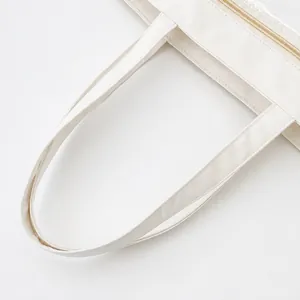 Detail view of large white tote bag featuring comfortable handles and a sturdy zipper closure