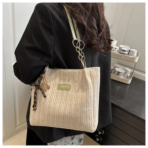 Detail of woven straw tote bag with green leather straps and floral ribbon decoration