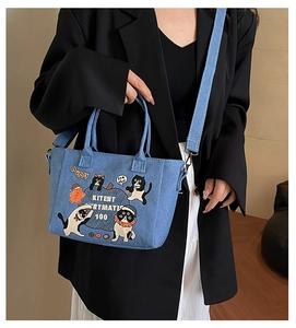 Detail of blue denim tote bag with cartoon cat illustrations and adjustable strap