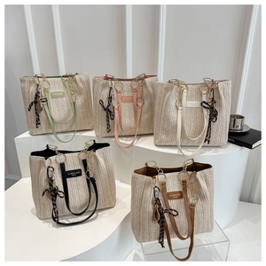 Straw tote bag detail with leather straps, gold chains and colorful silk scarves