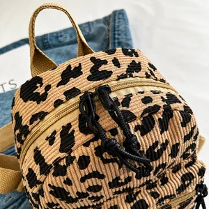 Detail of smooth black double zippers on leopard print corduroy mini backpack