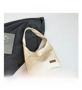 Detailed close-up of cream leather tote bag with front pocket and brown logo patch