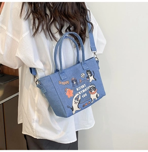 Detailed back view of a cartoon denim tote bag with cat graphics and adjustable strap