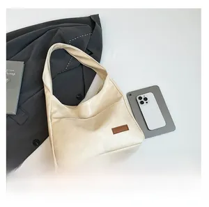Detail view of a beige minimalist HOBO shoulder bag styled with office commuter essentials