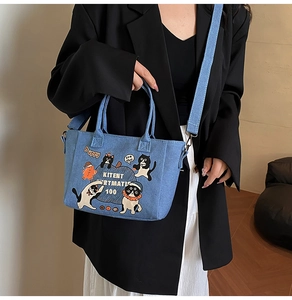 Light blue denim tote bag with cartoon cat prints worn with a black blazer outfit