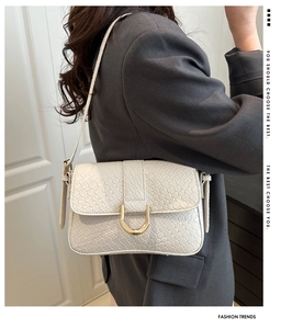 Détail d'un sac bandoulière blanc tissé avec une boucle en métal doré chic en forme de U