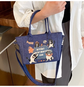 Detailed side view of denim tote bag with cartoon cat prints and adjustable shoulder strap