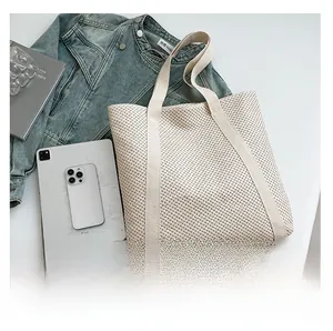 Détail d'un sac cabas en maille tressée beige avec de larges bretelles pour l'été