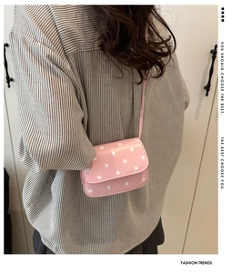 Close-up of pink polka dot crossbody bag worn by a model in a minimalist setting