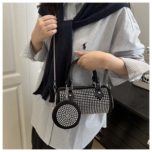 Détail du sac cylindrique noir punk avec rivets argentés et bandoulière en chaîne