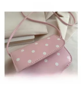 Detail showing pink and white polka dot mini crossbody bag with smooth PU texture