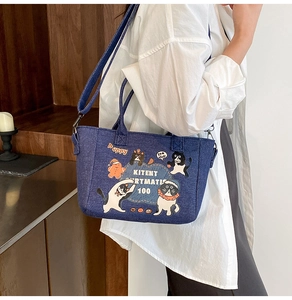 Detail of cartoon denim tote bag with cat embroidery and adjustable crossbody strap