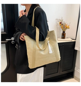Vue latérale d'un grand sac cabas en paille avec pompon blanc pour la plage ou le quotidien