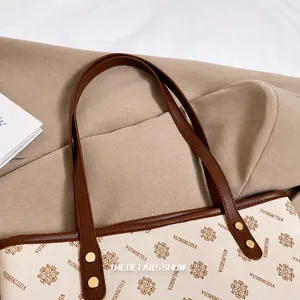 Detail view of reinforced brown leather handles with gold rivets on vintage tote bag