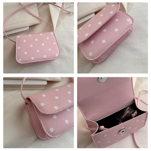 Detail view of pink polka dot mini crossbody bag showing metal magnetic closure and interior