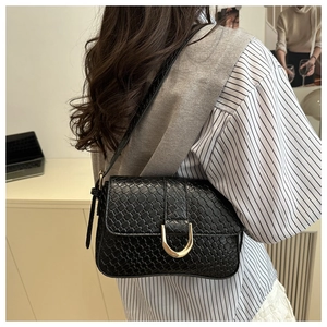 Détail d'un sac à bandoulière noir tressé avec boucle métallique dorée vintage
