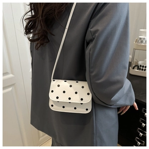 Polka dot crossbody bag detail shown on model in a casual grey blazer outfit