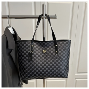 Detail van grote shopper met 'M' jacquardpatroon en goudkleurig logo-embleem