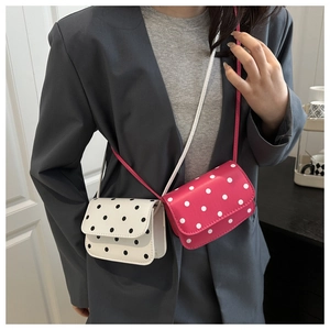 Close-up of mini polka dot crossbody bags in white and pink on a fashion model