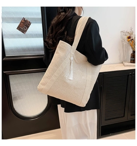 Détail de texture du sac cabas tissé crème avec pampille élégante et bandoulière large