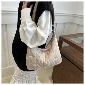Detail van de beige gewatteerde nylon draagtas met kleurrijke stiksels en schouderriem