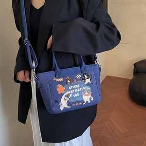 Blue denim tote bag with cartoon cat prints and adjustable shoulder strap for casual wear