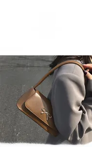 Détail du sac à bandoulière en cuir marron avec une boucle dorée élégante en forme de nœud