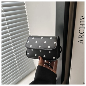 Detailed close-up of a stylish black polka dot crossbody bag with leather strap