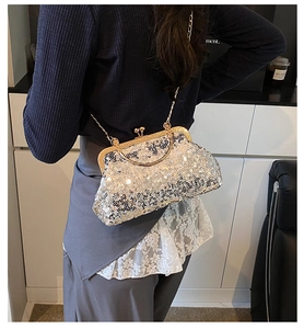 Close-up of silver sequin evening bag with gold metal handle and delicate chain strap
