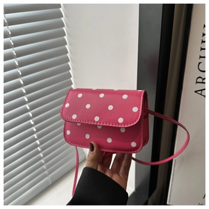 Macro shot of a pink polka dot mini crossbody bag being held to show compact size
