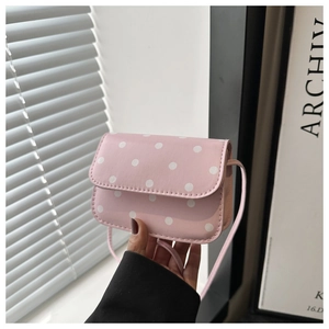 Detail view of mini pink polka dot handbag with slim shoulder strap and flap closure