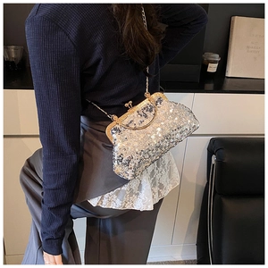 Silver sequin evening clutch bag with gold metal frame worn as a crossbody shoulder bag