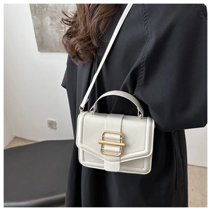 Detail of white PU leather square bag featuring a large gold metal buckle and top handle
