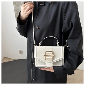 Detail of white vintage crossbody square bag with gold metallic buckle on a black trench coat