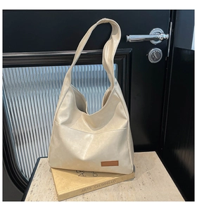 Detail of minimalist cream tote bag with textured faux leather and small brown tag accent