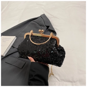 Close-up of black sequin evening clutch bag with golden metal clasp and chain strap