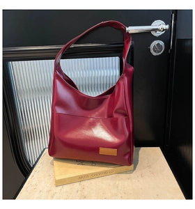 Detail of burgundy tote bag with brown label placed on a book for office daily use