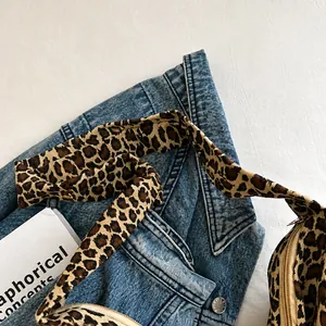 Detailed close-up of the wide fabric shoulder strap and gold zipper on a leopard print tote