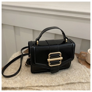 Detailed macro view of glossy black leather handbag with a large gold metallic buckle