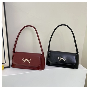 Détail de sacs baguette en cuir brillant bordeaux et noir avec boucles dorées