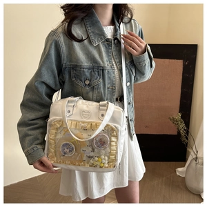Detailweergave van witte Ita-tas met transparant venster, kant en pluche accessoires