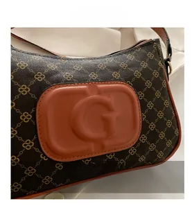 Detail view of vintage monogram PVC texture and orange leather G emblem on handbag