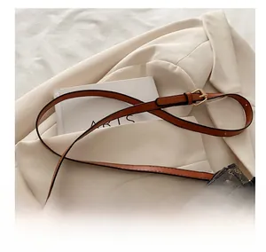 Close-up of adjustable brown leather shoulder strap with gold buckle on patterned bag
